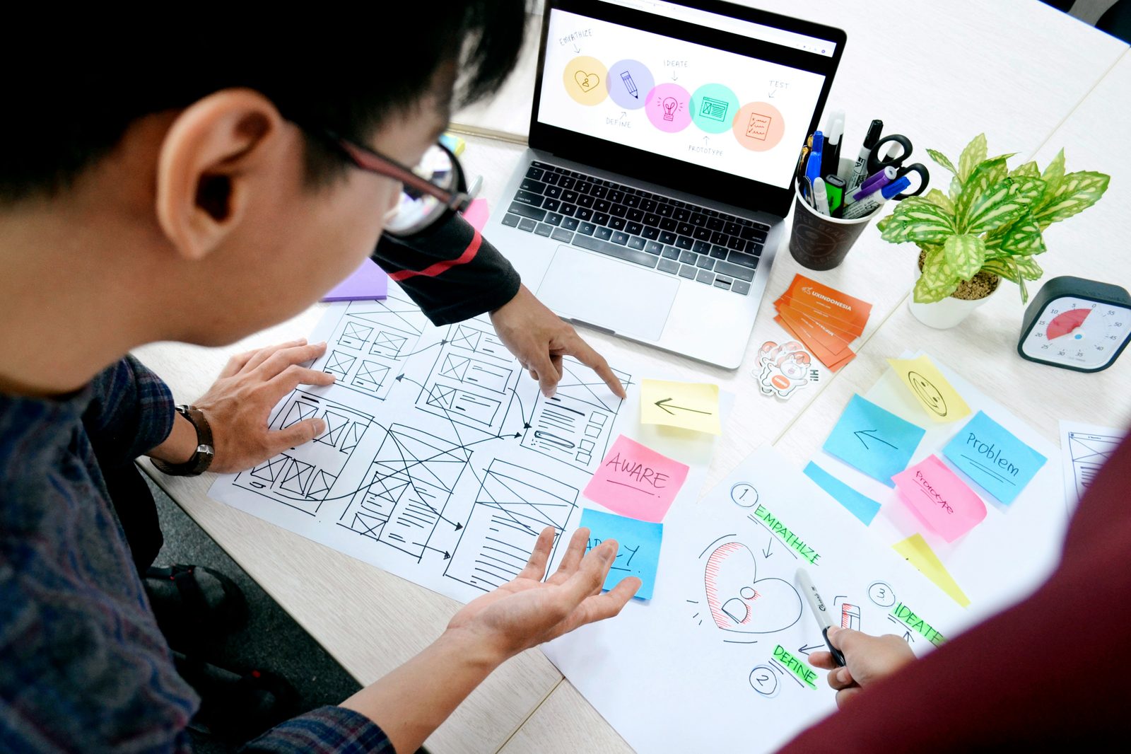 Designer mapping a product process with wireframes and sticky notes