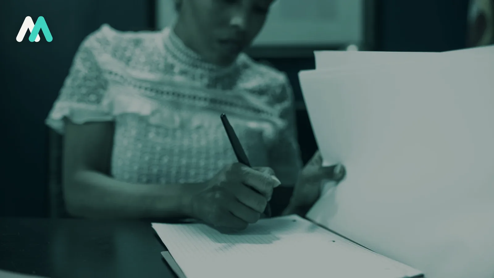 A person completing paperwork at a desk.