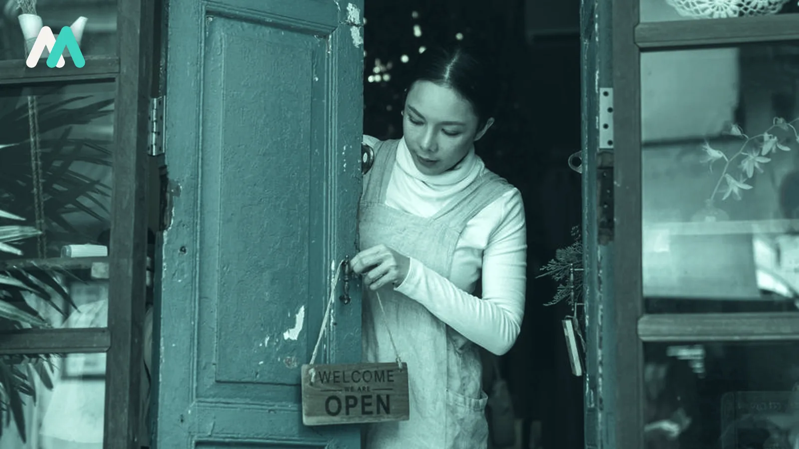 A shop owner hanging the open sign on the door.