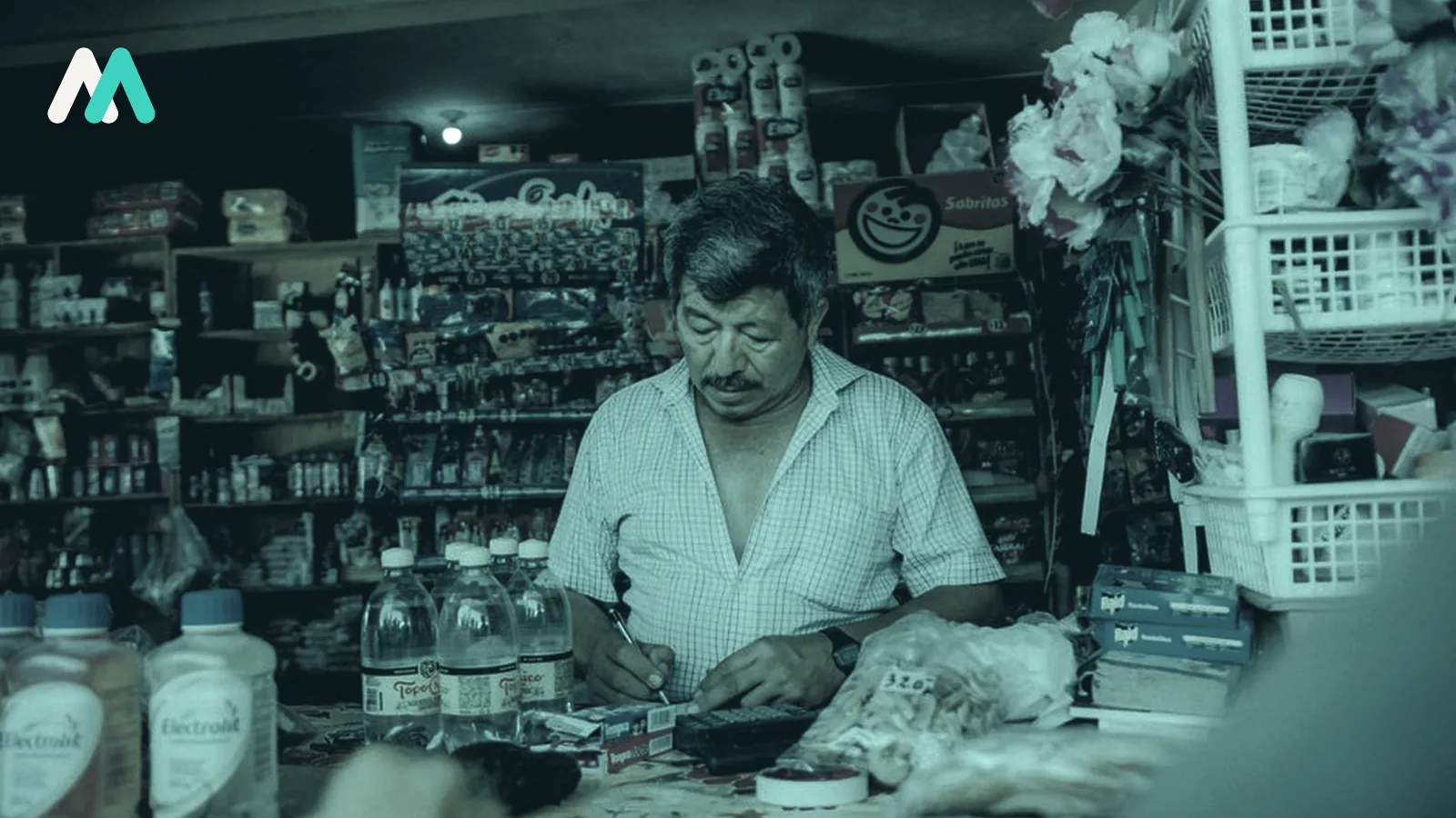 A shopkeeper behind the counter of a packed independent corner shop.
