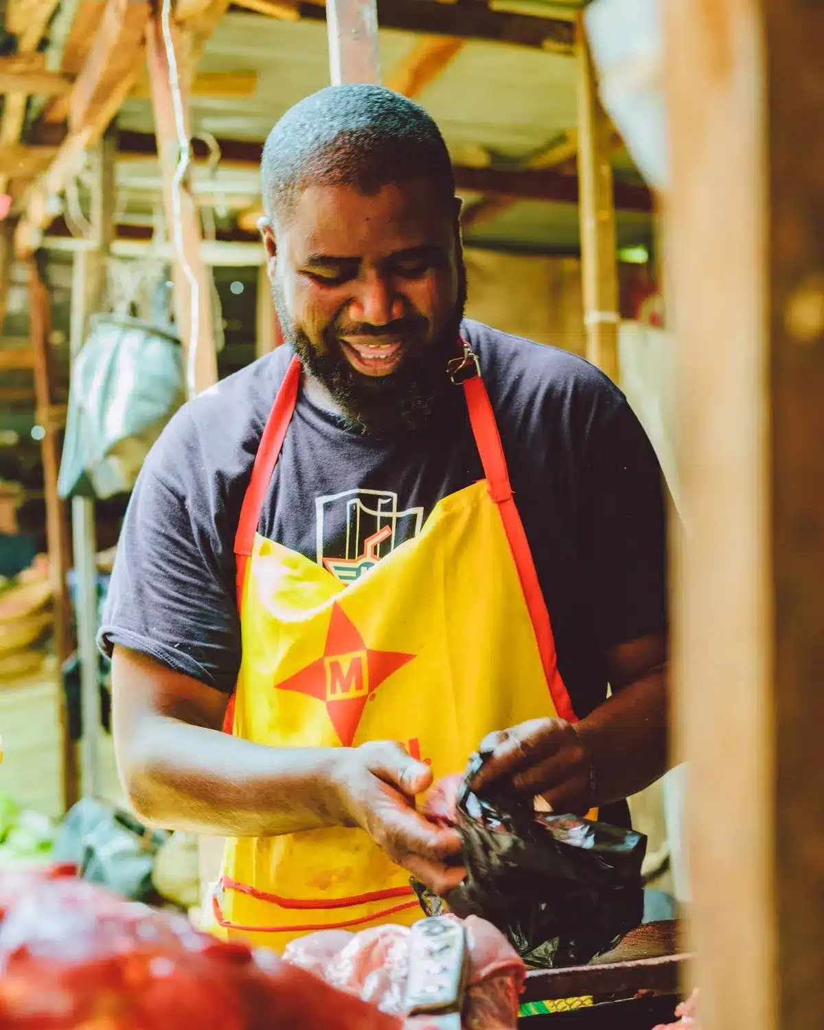 A smiling butcher serving at an outdoor market stall