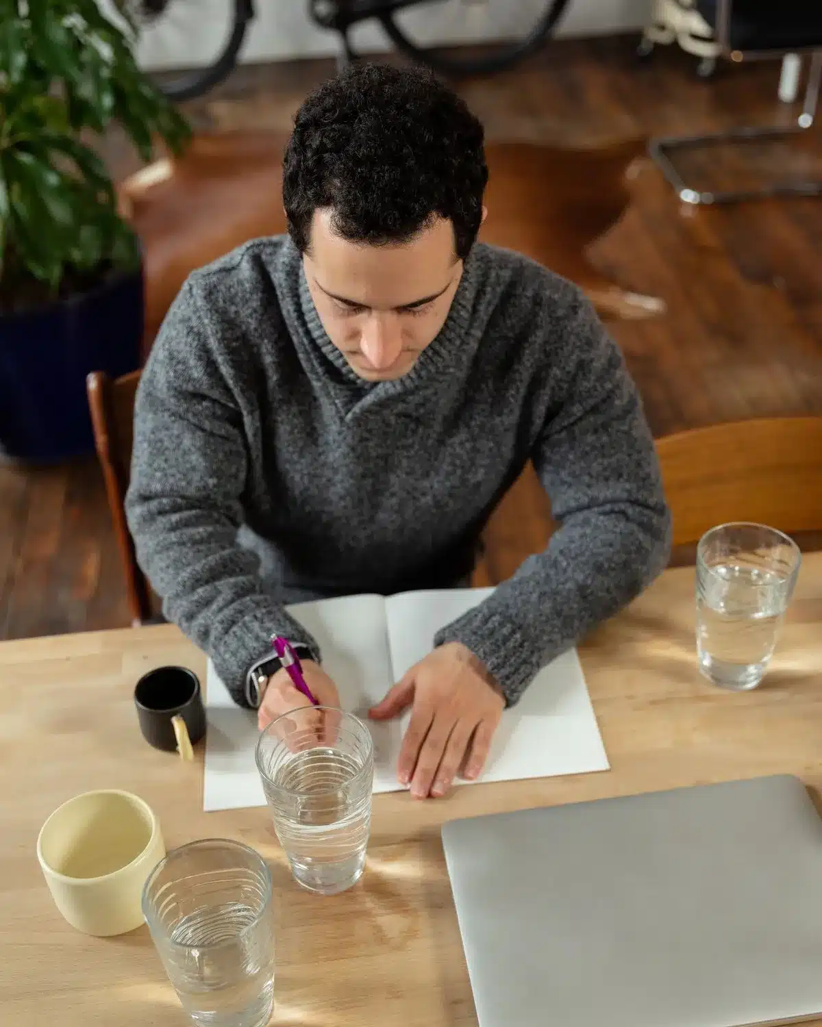 A man writing a plan in a notebook at a wooden table