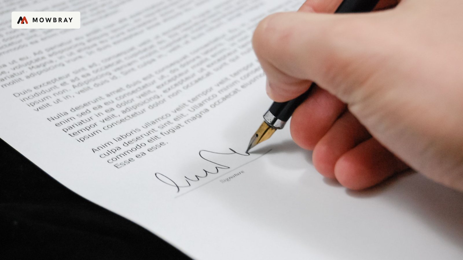 A hand signing a document with a fountain pen