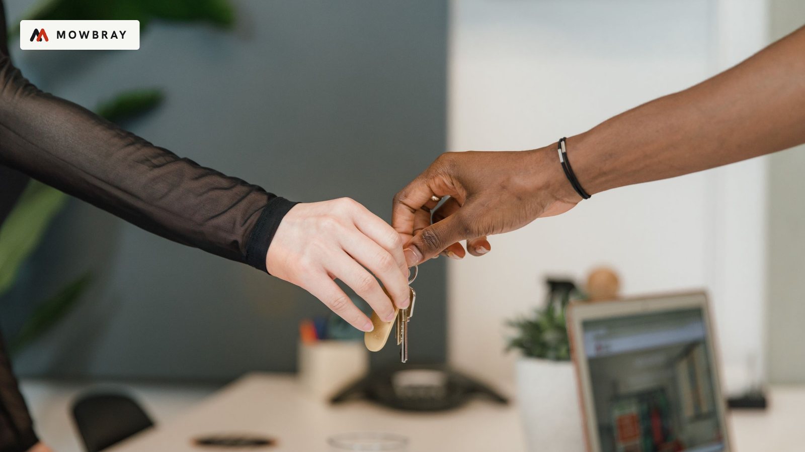 One person handing a set of keys to another across a desk