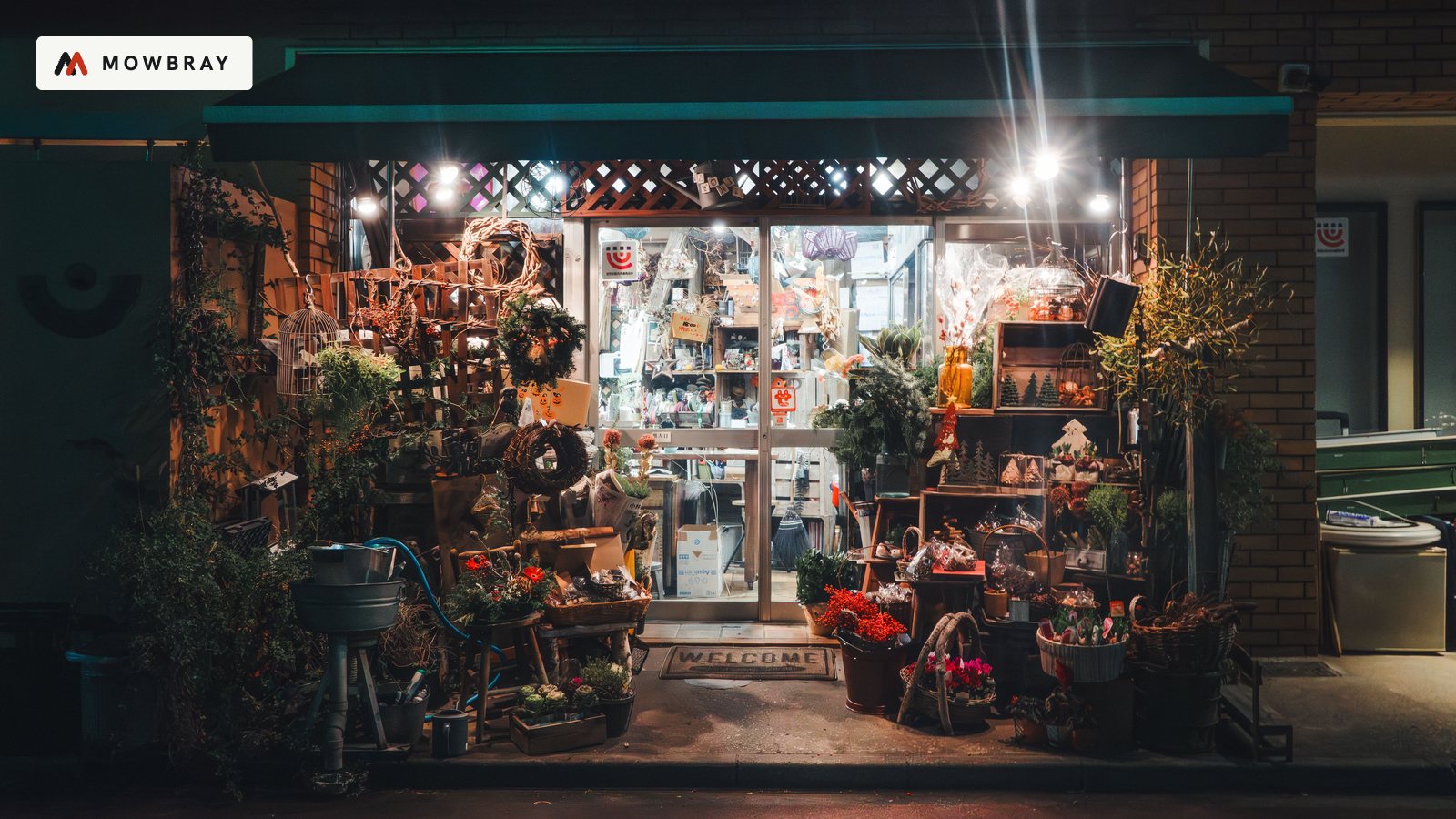 A small florist's shop front lit up at dusk